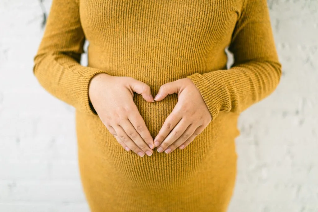 Woman making a heart shape with her hands over her stomach, representing gut health and digestion