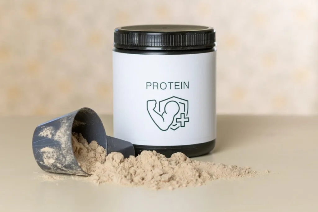 Jar of vegan protein powder next to a measuring scoop of protein powder