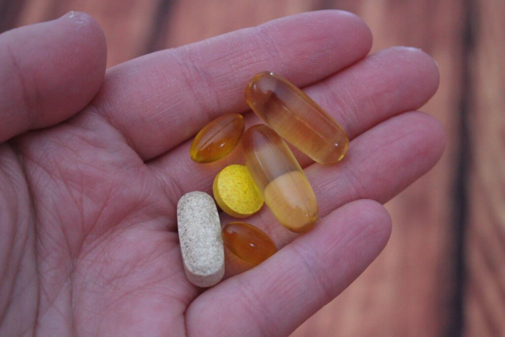 Person holding vitamin and supplement pills in their hand