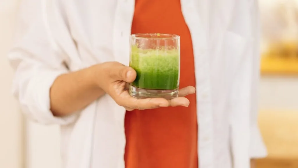 Close-up of a person holding a fresh green smoothie — well-blended plant protein shake